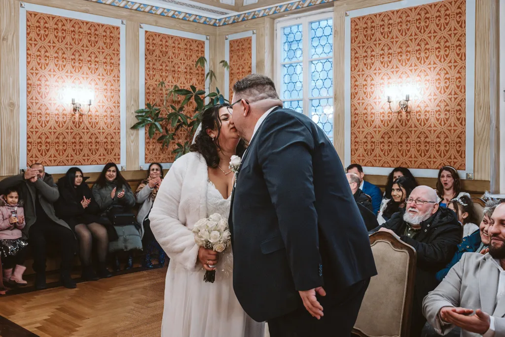Der erste Kuss als Ehepaar Der erste Kuss des frisch vermählten Brautpaares nach dem Ja-Wort im Trausaal. Emotionale Hochzeitsfotografie während der Zeremonie.