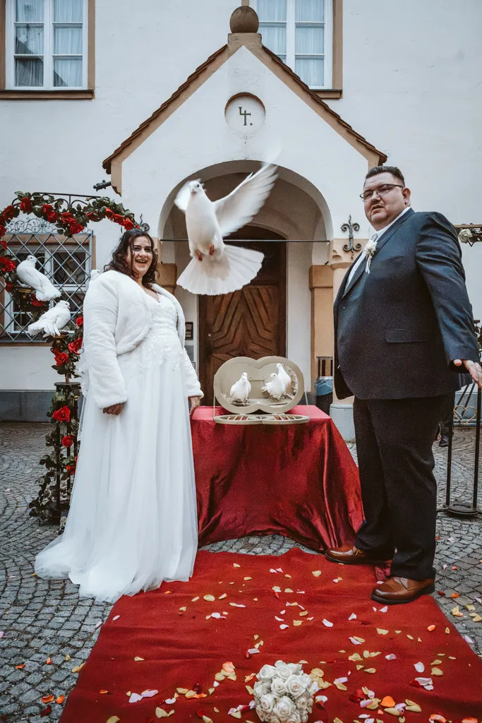 Der Flug der Hochzeitstauben Dynamische Aufnahme beim Fliegenlassen der Hochzeitstauben: Weiße Tauben steigen vor dem Brautpaar in den Himmel auf.