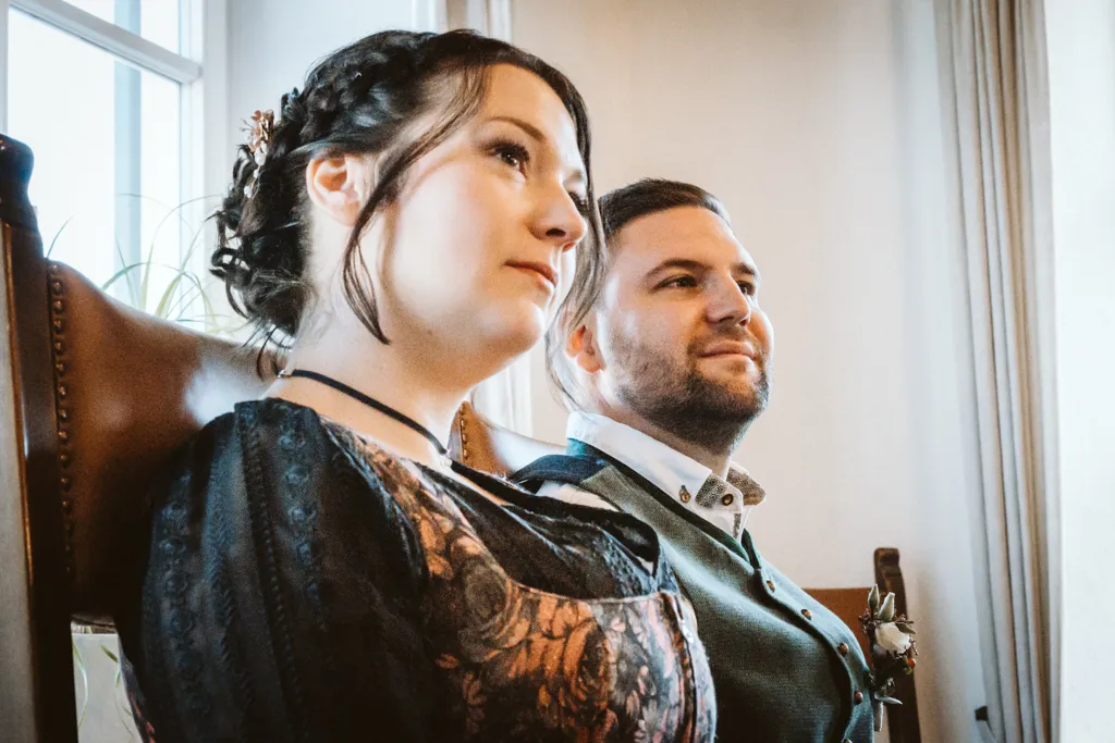 Zuhören und Genießen: Das Brautpaar im festlichen Moment. Brautpaar, von unten fotografiert, hört der Rede des Standesbeamten zu.