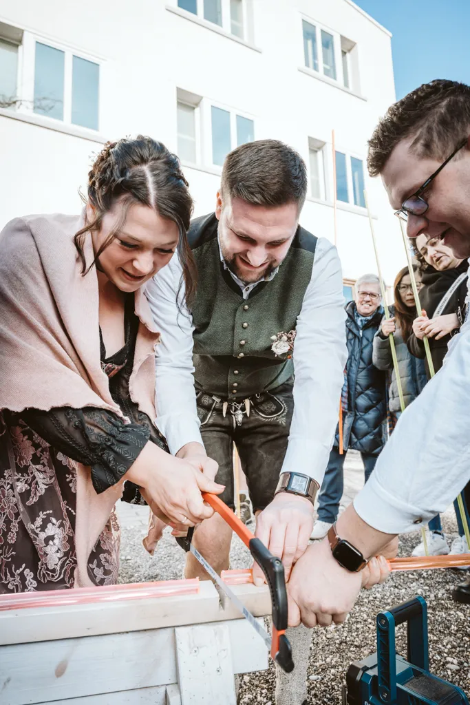 Gemeinsam ans Ziel: Brautpaar sägt Kunststoff vor dem Rathaus. Brautpaar sägt Kunststoffstab vor dem Rathaus.