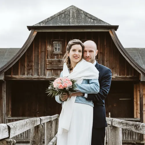 Ich habe den Bräutigam dabei fotografiert, wie er seine Braut liebevoll von hinten umarmt, während sie den Brautstrauß hält. Eine innige Momentaufnahme aus meiner Hochzeitsreportage am Ammersee.
