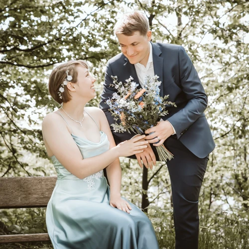 Die liebevolle Übergabe des Brautstraußes vom Bräutigam an seine sitzende Braut. Ich war dabei, um diesen zärtlichen Augenblick als Ihr Hochzeitsfotograf festzuhalten.